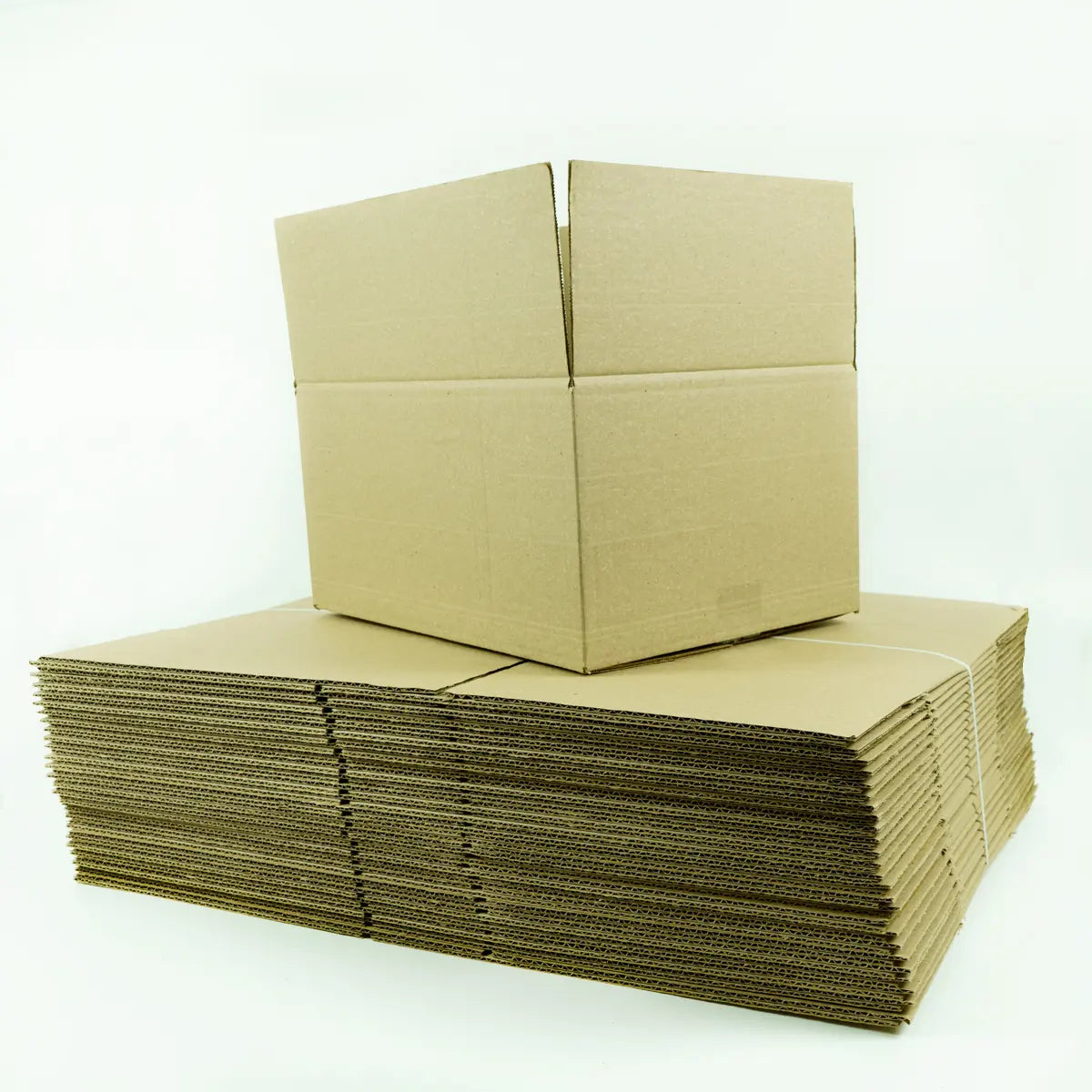 Cajas de cartón planas y apiladas, listas para armar, junto a una caja armada